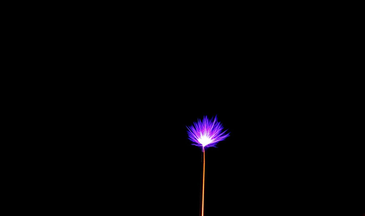 Single purple electrostatic charge against a black background
