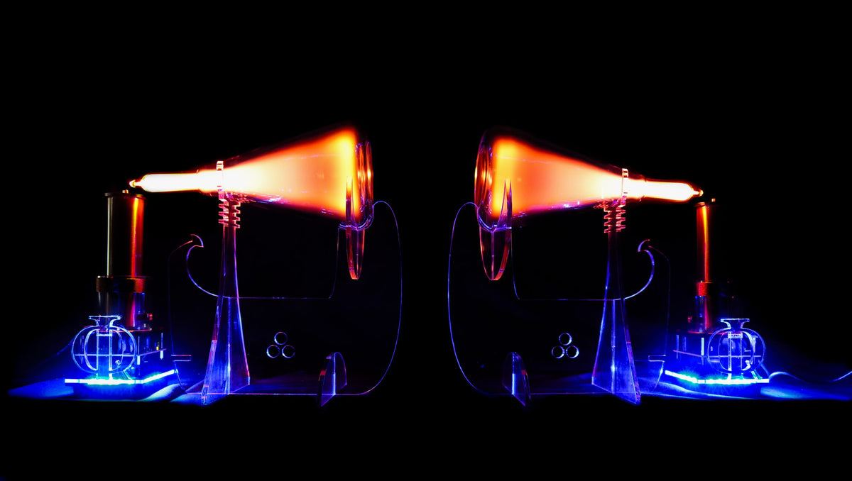 Two illuminated glass beakers with a glowing orange light on a black background