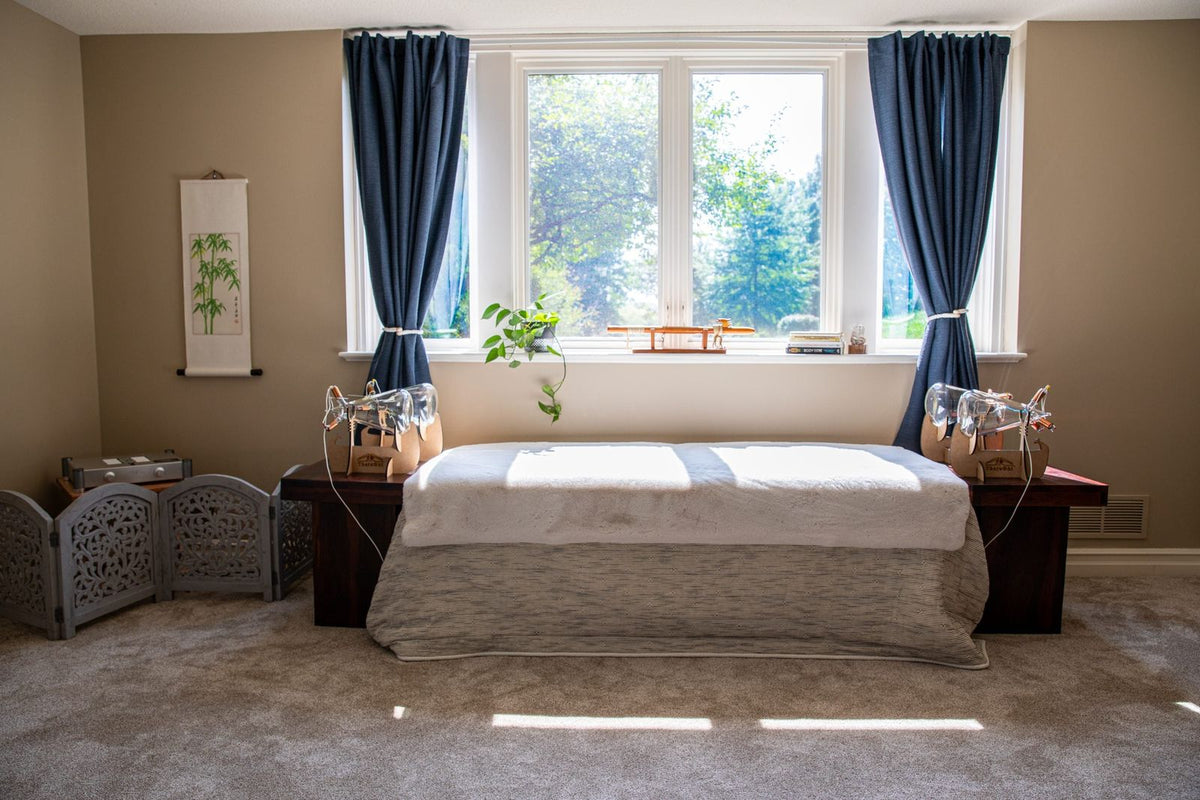 Neatly made bed in a room with large windows and decorative elements and Theraphi quad setup.
